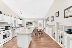 Open-concept kitchen featuring white cabinetry, light-toned countertops, and wood-finish flooring - 