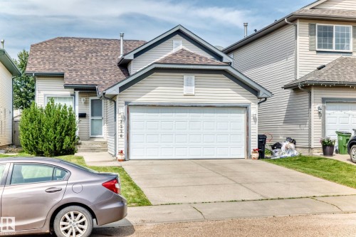 Two-story residence featuring light-toned siding, a multi-pane garage door, and a brown shingle roof - 3226 30 Avenue Nw, Edmonton, AB - Outdoor
