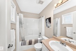 Full bathroom featuring a white tub and shower combination with a single lever faucet, a window with horizontal blinds, and a vanity with an integrated sink and mirror - 
