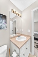 Bathroom vanity featuring a single basin sink, laminate countertop, and white cabinetry with silver-tone hardware - 
