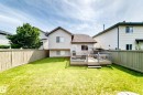 Expansive fenced backyard featuring a wood deck, manicured lawn, and mature perimeter trees - 3226 30 Avenue Nw, Edmonton, AB  - Outdoor With Deck Patio Veranda 
