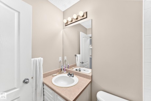 Bathroom featuring a vanity with an integrated sink, a large wall-mounted mirror, and a four-bulb vanity light fixture - 3226 30 Avenue Nw, Edmonton, AB - Indoor Photo Showing Bathroom