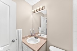 Bathroom featuring a vanity with an integrated sink, a large wall-mounted mirror, and a four-bulb vanity light fixture - 