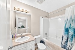 Full bathroom featuring a single vanity with a laminate countertop, built-in cabinetry, and a bathtub with a shower enclosure - 