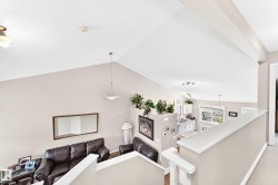 Open-concept living space with vaulted ceilings, neutral wall tones, and hardwood-style flooring - 