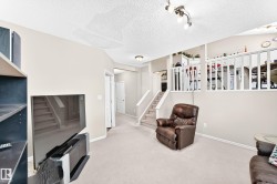 Carpeted lower level featuring a multi-level design with a white railing overlooking an upper area - 