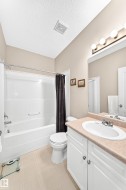 Full bathroom featuring a single white vanity with a light-toned countertop, a tub/shower combination, and light-colored flooring - 