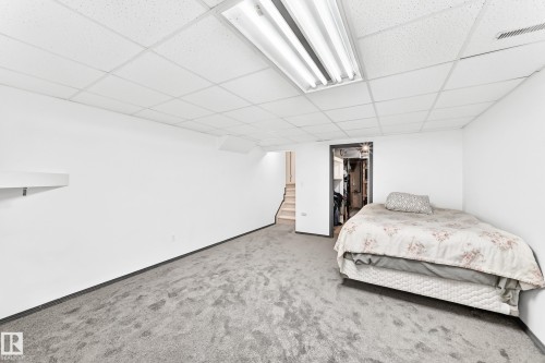 Spacious room featuring white walls, gray carpet flooring, and a drop ceiling with fluorescent lighting - 3226 30 Avenue Nw, Edmonton, AB - Indoor