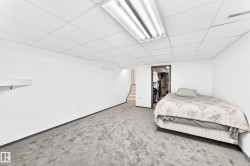 Spacious room featuring white walls, gray carpet flooring, and a drop ceiling with fluorescent lighting - 
