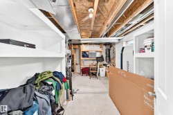 Utility space featuring exposed ceiling joists, open shelving, a concrete floor, and interior lighting - 