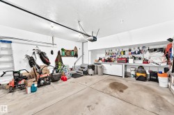 Spacious garage with concrete flooring, built-in shelving, white walls, and track lighting - 