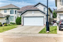 Two-story residential exterior with light-colored horizontal siding and dark trim - 