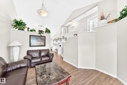 Vaulted ceilings enhance this living space featuring wood-finish flooring and a decorative architectural ledge - 