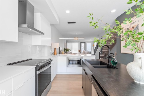 Contemporary kitchen featuring a dual-basin sink with a matte black faucet, integrated dishwasher, stainless steel appliances, and white cabinetry - 8047 227 Street Nw, Edmonton, AB - Indoor Photo Showing Kitchen With Double Sink With Upgraded Kitchen
