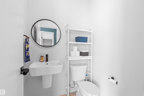 Pedestal sink with a black-framed circular mirror and a wall-mounted faucet - 8047 227 Street Nw, Edmonton, AB - Indoor Photo Showing Bathroom