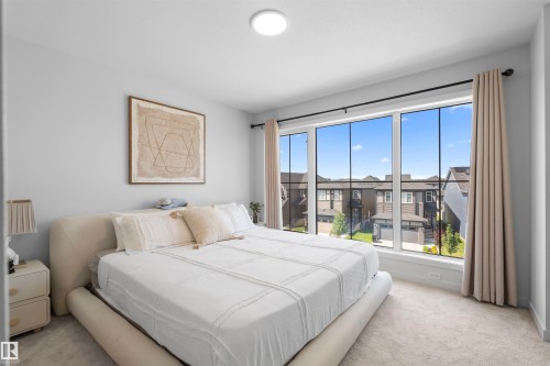 Spacious room featuring light gray wall paint, a large picture window with black trim, and light-colored carpeting - 8047 227 Street Nw, Edmonton, AB - Indoor Photo Showing Bedroom
