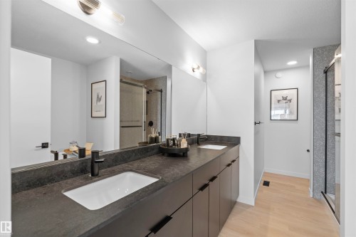 Dual vanity with dark countertops and integrated sinks - 8047 227 Street Nw, Edmonton, AB - Indoor Photo Showing Bathroom