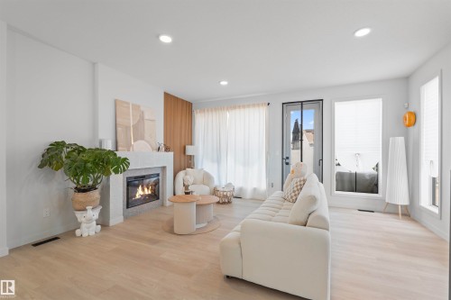 Bright living space featuring light wood-finish flooring - 8047 227 Street Nw, Edmonton, AB - Indoor Photo Showing Living Room With Fireplace