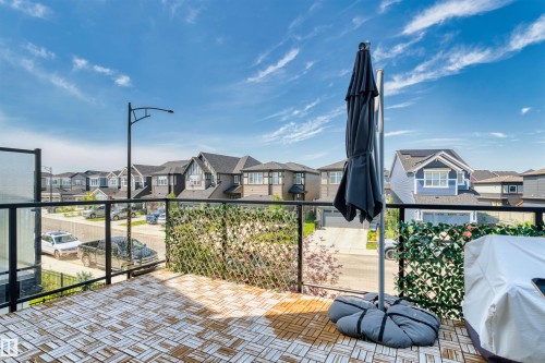 Outdoor patio featuring wood-finish decking, glass panel railings, and a privacy screen - 8047 227 Street Nw, Edmonton, AB - Outdoor With Balcony