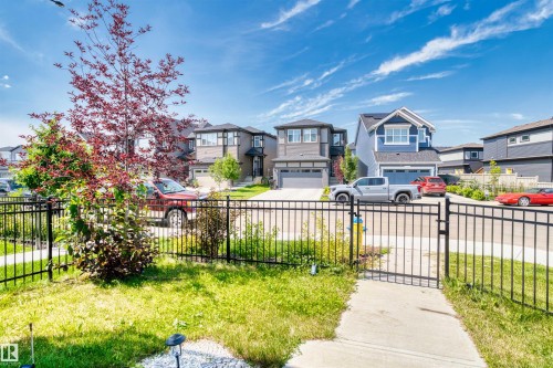 Black metal fencing enclosing a front yard with a concrete pathway - 8047 227 Street Nw, Edmonton, AB - Outdoor