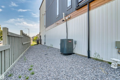 Gravel side yard featuring a light-toned wood fence and a contemporary exterior with vertical white siding - 8047 227 Street Nw, Edmonton, AB - Outdoor With Exterior