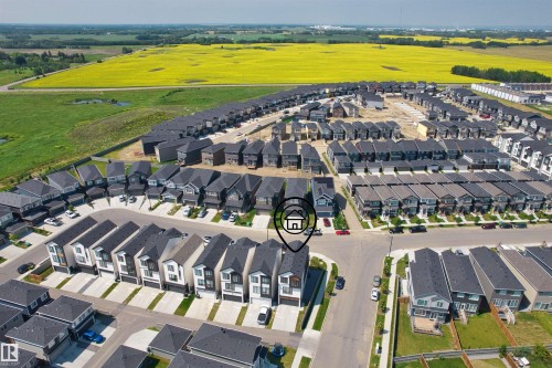 Aerial perspective showcasing a modern residential neighborhood with a variety of housing styles, featuring a prominent yellow field bordering the community - 8047 227 Street Nw, Edmonton, AB - Outdoor With View