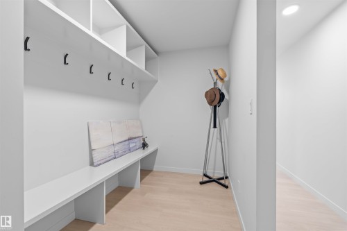 Custom built-in mudroom storage featuring white shelving, integrated bench seating, and black hanging hooks - 8047 227 Street Nw, Edmonton, AB - Indoor