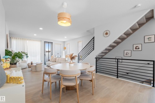 Open-concept living area featuring light wood-finish flooring, a contemporary staircase with black horizontal railings, and recessed lighting - 8047 227 Street Nw, Edmonton, AB - Indoor Photo Showing Dining Room