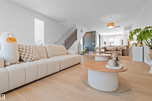 Open-concept living space featuring wood-finish flooring, a modern staircase with metal railings, recessed lighting, and a kitchen island with seating - 8047 227 Street Nw, Edmonton, AB - Indoor Photo Showing Living Room