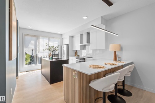 Contemporary kitchen featuring light wood-finish flooring and a white color palette - 8047 227 Street Nw, Edmonton, AB - Indoor
