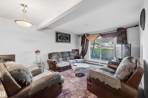 Living room featuring a sliding glass door, overhead semi-flush mount light fixture, and white painted walls - #143 301 Clareview Station Dr Nw, Edmonton, AB - Indoor Photo Showing Living Room