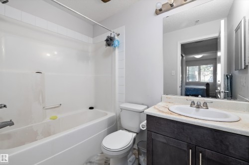 Bathroom featuring a dark wood-finish vanity with a light-toned countertop, an undermount sink, and a large wall-mounted mirror - #143 301 Clareview Station Dr Nw, Edmonton, AB - Indoor Photo Showing Bathroom