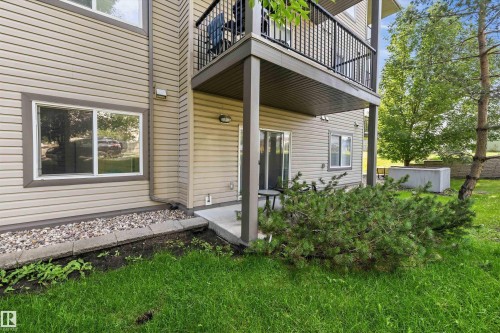 Exterior featuring tan horizontal siding, a private concrete patio, and an upper-level balcony with black metal railings - #143 301 Clareview Station Dr Nw, Edmonton, AB - Outdoor With Exterior