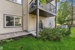 Exterior featuring tan horizontal siding, a private concrete patio, and an upper-level balcony with black metal railings - 