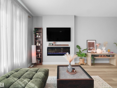 Integrated electric fireplace with wood-finish mantel and built-in shelving - #81 6905 25 Av Sw, Edmonton, AB - Indoor Photo Showing Living Room With Fireplace
