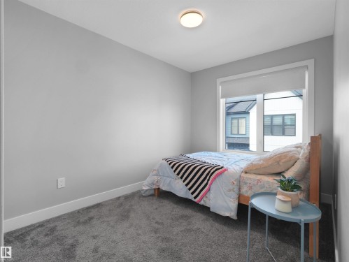 Recessed window with roller shade, neutral wall paint, white trim, and ceiling-mounted light fixture - #81 6905 25 Av Sw, Edmonton, AB - Indoor Photo Showing Bedroom