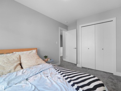 Room featuring light gray walls, gray carpet, and white bi-fold closet doors with brushed nickel hardware - #81 6905 25 Av Sw, Edmonton, AB - Indoor Photo Showing Bedroom