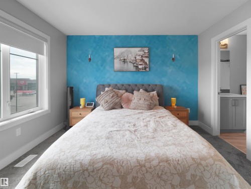 Bedroom featuring a textured accent wall and a window with roller blind - #81 6905 25 Av Sw, Edmonton, AB - Indoor Photo Showing Bedroom