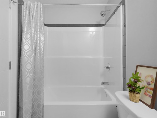 White acrylic tub and shower combination with chrome fixtures and showerhead - #81 6905 25 Av Sw, Edmonton, AB - Indoor Photo Showing Bathroom