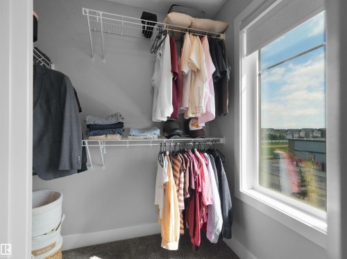 Walk-in closet featuring wire shelving, hanging rods, and a large window with roller shade - #81 6905 25 Av Sw, Edmonton, AB - Indoor With Storage