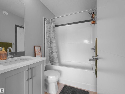 Contemporary bathroom featuring a light gray vanity with chrome hardware, an integrated sink, and a rectangular mirror - #81 6905 25 Av Sw, Edmonton, AB - Indoor Photo Showing Bathroom