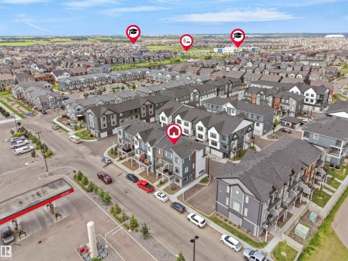 Aerial perspective of a contemporary residential development featuring multi-story townhomes with dark gray and light gray siding - #81 6905 25 Av Sw, Edmonton, AB - 