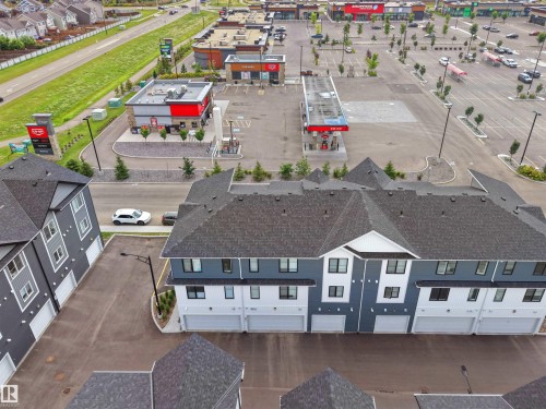 Contemporary multi-story townhome featuring a dark gray shingle roof and a facade with light gray and white siding - #81 6905 25 Av Sw, Edmonton, AB - Outdoor