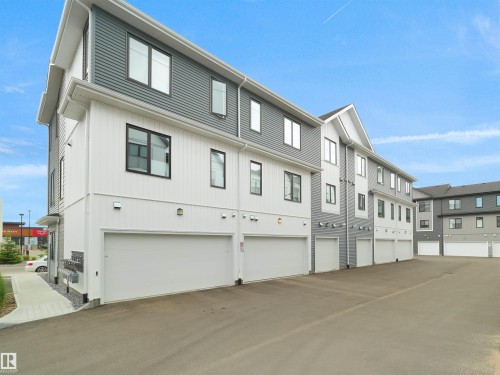 Contemporary townhome architecture featuring a multi-story design with contrasting white and gray siding - #81 6905 25 Av Sw, Edmonton, AB - Outdoor