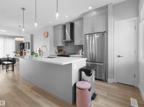 Contemporary kitchen island featuring an undermount sink, gooseneck faucet, and pendant lighting - #81 6905 25 Av Sw, Edmonton, AB - Indoor Photo Showing Kitchen With Upgraded Kitchen