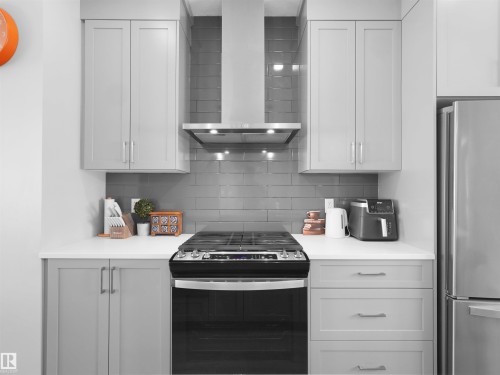 Kitchen featuring light gray shaker-style cabinetry, white countertops, and a gray subway tile backsplash - #81 6905 25 Av Sw, Edmonton, AB - Indoor Photo Showing Kitchen