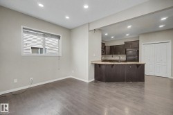 Open-concept living space featuring wood-finish flooring, recessed lighting, and a window with blinds - 