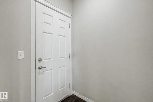 Six-panel interior door with brushed nickel hardware, light gray wall paint, white trim, and dark wood-finish flooring - 315 Watt Boulevard Sw, Edmonton, AB 