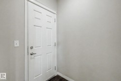 Six-panel interior door with brushed nickel hardware, light gray wall paint, white trim, and dark wood-finish flooring - 
