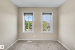 Room featuring two large windows with roller shades, neutral tone walls, and gray carpet - 